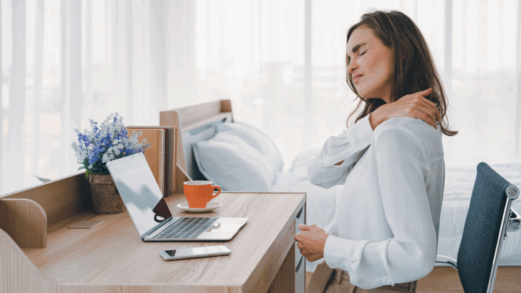 A lady sitting at desk with sore shoulder